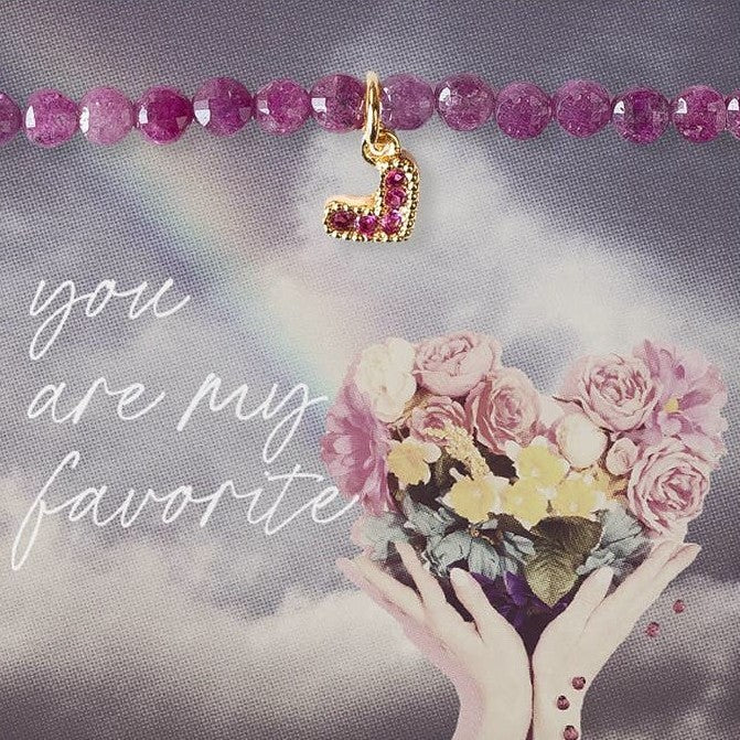 Closeup of reddish purple ruby beaded bracelet with tiny heart charm