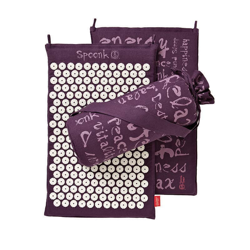 Dark purple acupressure mat with white pressure spikes and relaxing and inspiring words written on the fabric in light purple. Drawstring carrying case in coordinating fabric.