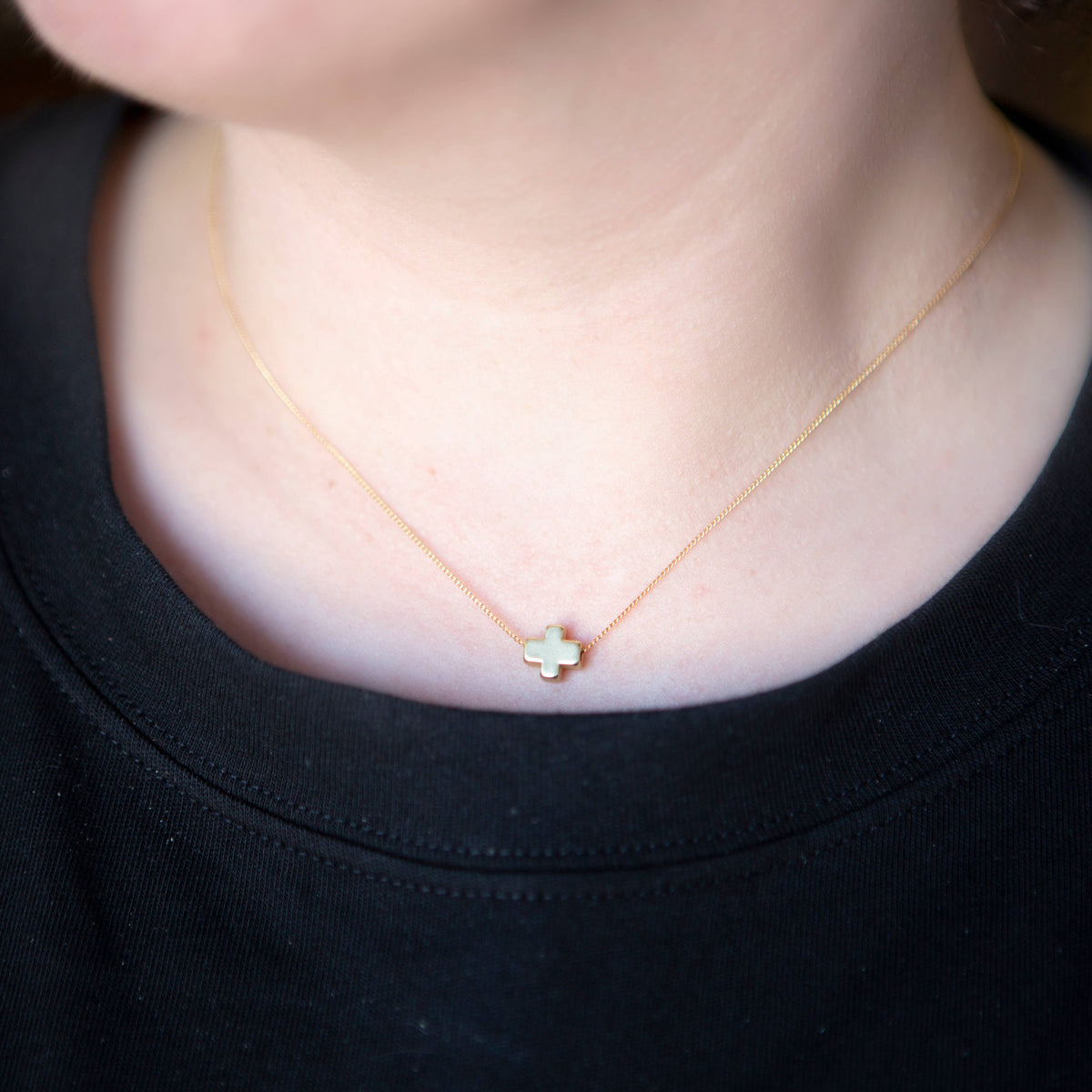 Model wearing the gold cross necklace from Lenny & Eva's Faith Over Fear collection