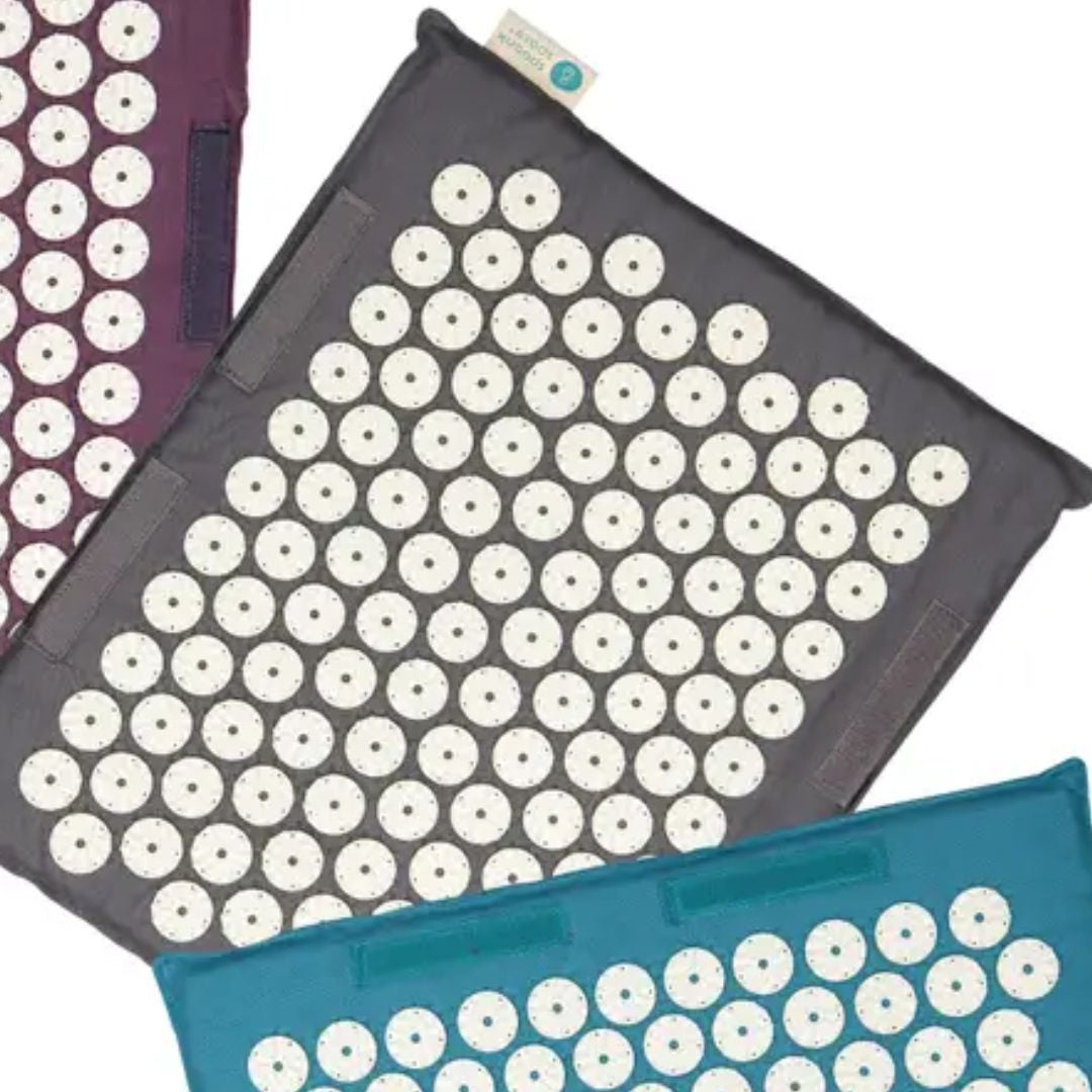 Travel size acupressure mats in purple, gray, and teal