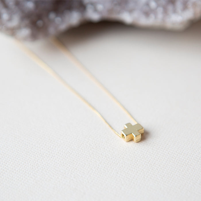 Tiny gold cross necklace on thin gold chain from the Faith Over Fear collection by Lenny & Eva
