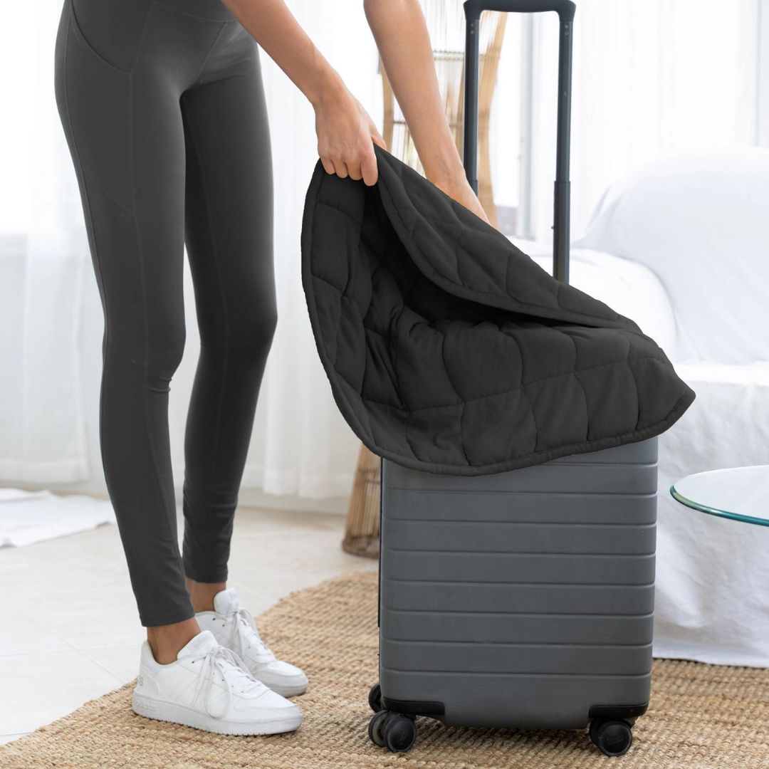 Black Nodpod weighted throw laying on top of a suitcase