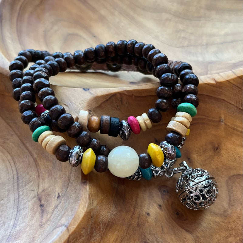 Dark brown wood bead wrap bracelet with green, pink, yellow and other brightly colored beads. Silver cage pendant holds lava rock bead for essential oils.
