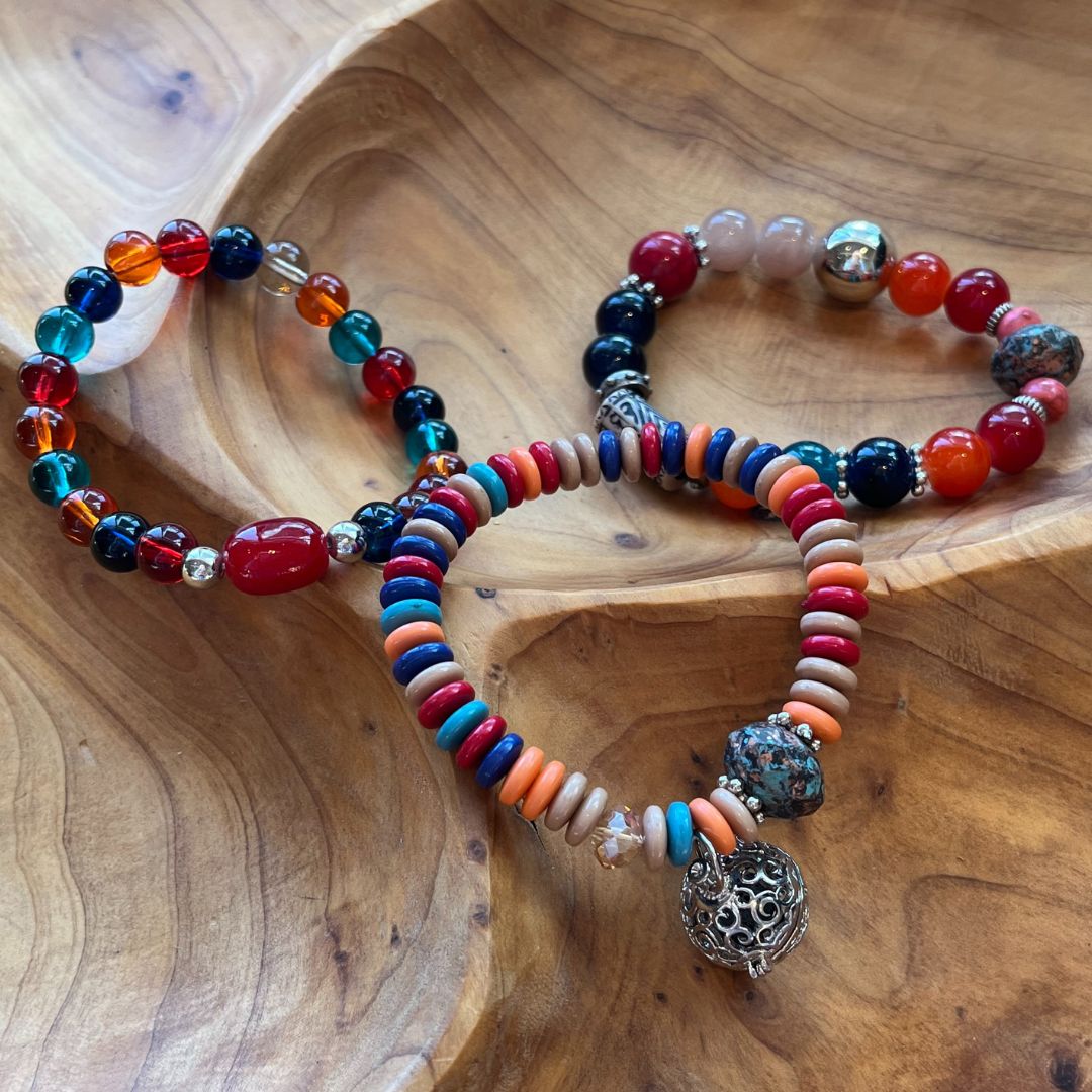 Three beaded bracelets in shades of reds, oranges, turquoise.