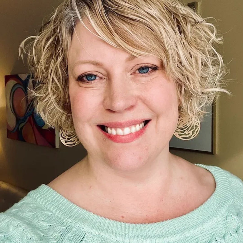 Woman with short wavy blond hair and green sweater