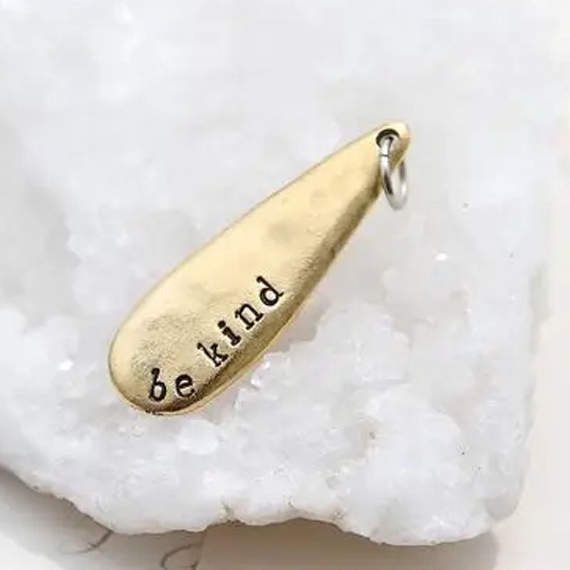 Gold teardrop necklace pendant stamped with "be kind"