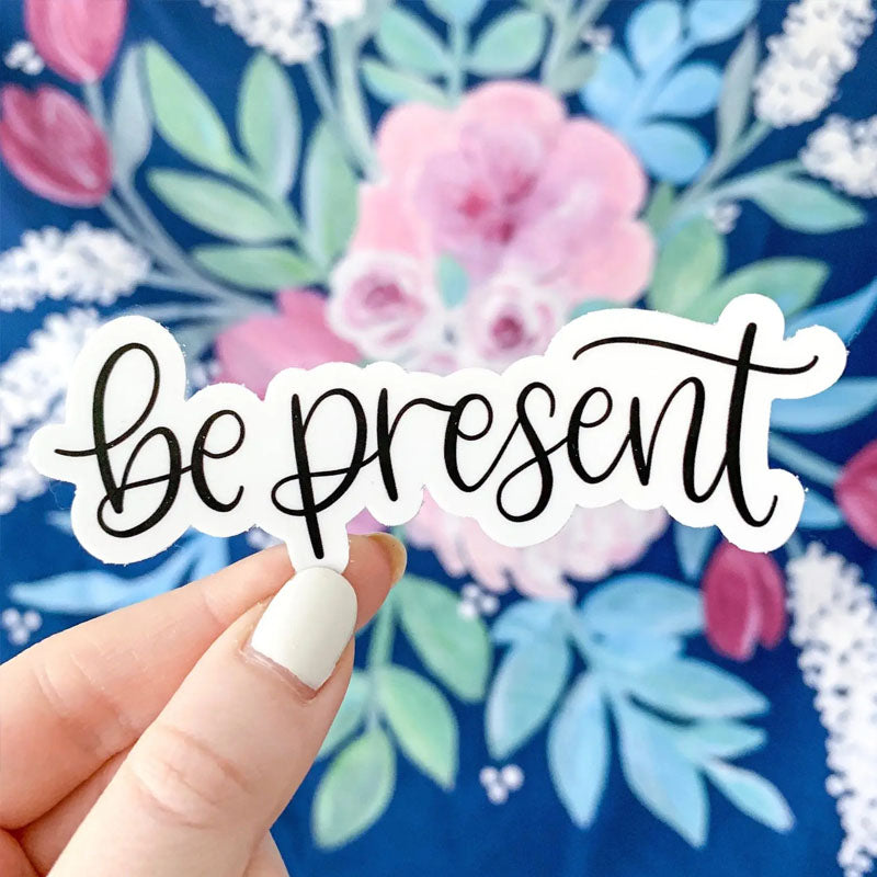 Sticker with a white background and "be present" written in black