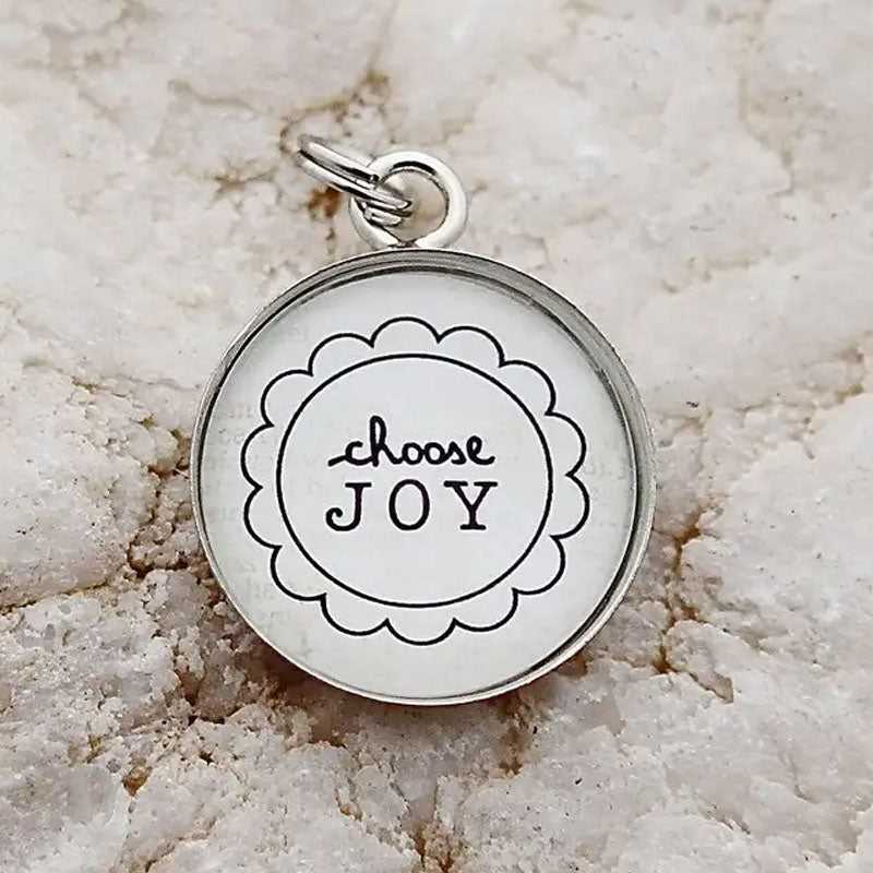 Round necklace pendant with the words "choose joy" inside a flower design.