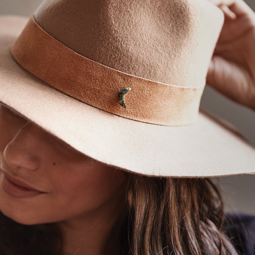 Crescent shaped pin attached to the band of tan fedora hatfedora