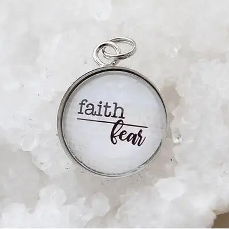 Round necklace pendant with faith above a line and fear below it.
