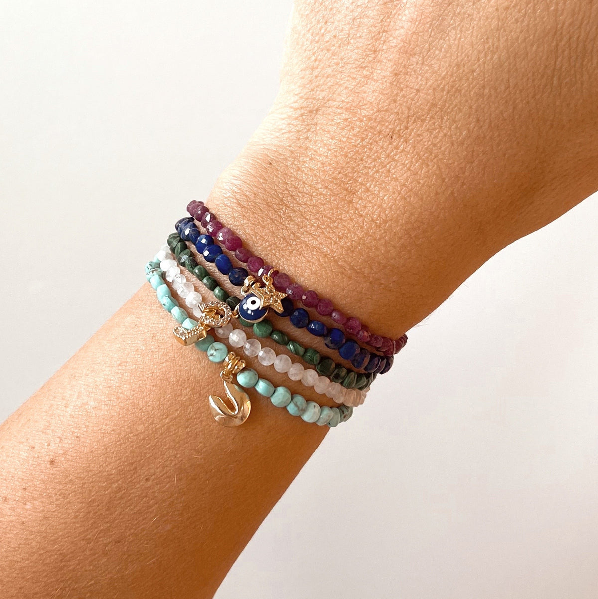 Stack of delicate Good Fortune collection bracelets on wrist