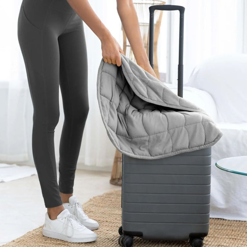 Gray travel size weighted blanket sitting on top of suitcase