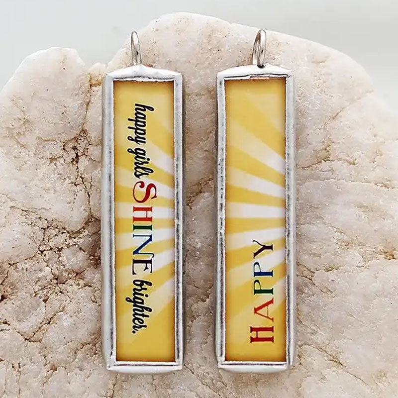 Reversible necklace pendant with a yellow background and the word "happy" on one side and "happy girls shine brighter" on the reverse.