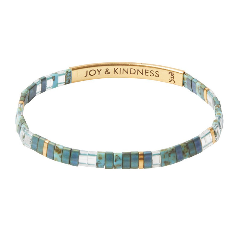Bracelet in shades of aqua marines, gold, and clear beads with a gold band that says "JOY & KINDNESS"