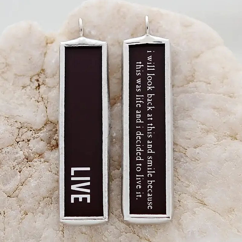 Necklace pendant with a black background that says "live" on one side and the other side reads "I will look back at this and smile because this was life and I decided to live it."