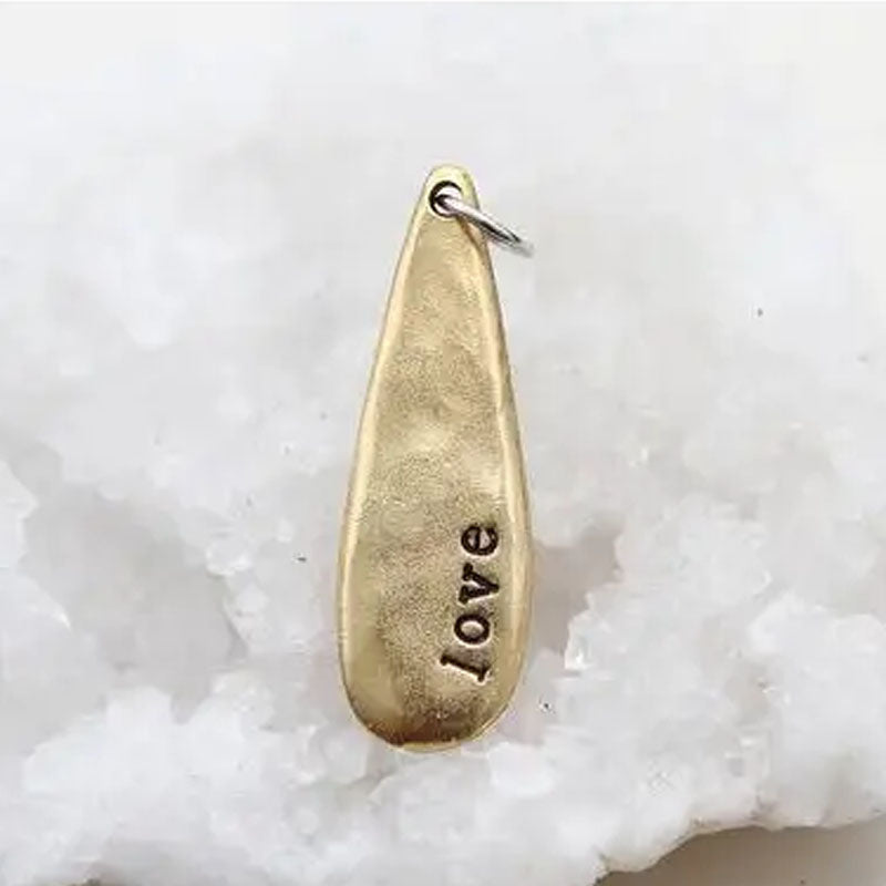 Gold teardrop shaped necklace pendant stamped with the word "love"