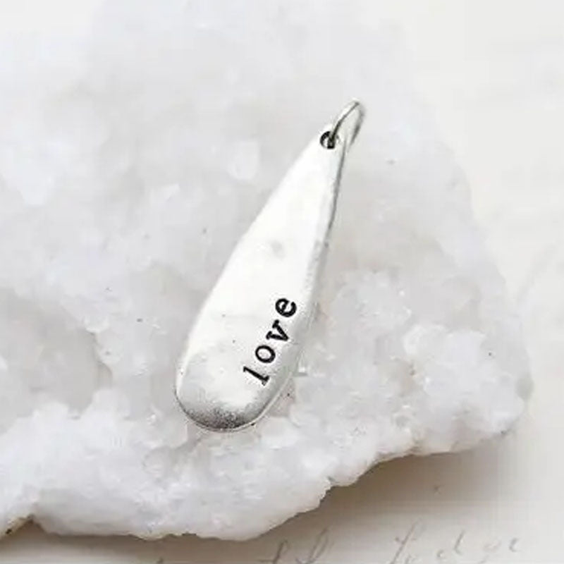 Silver teardrop shaped necklace pendant stamped with the word "love"