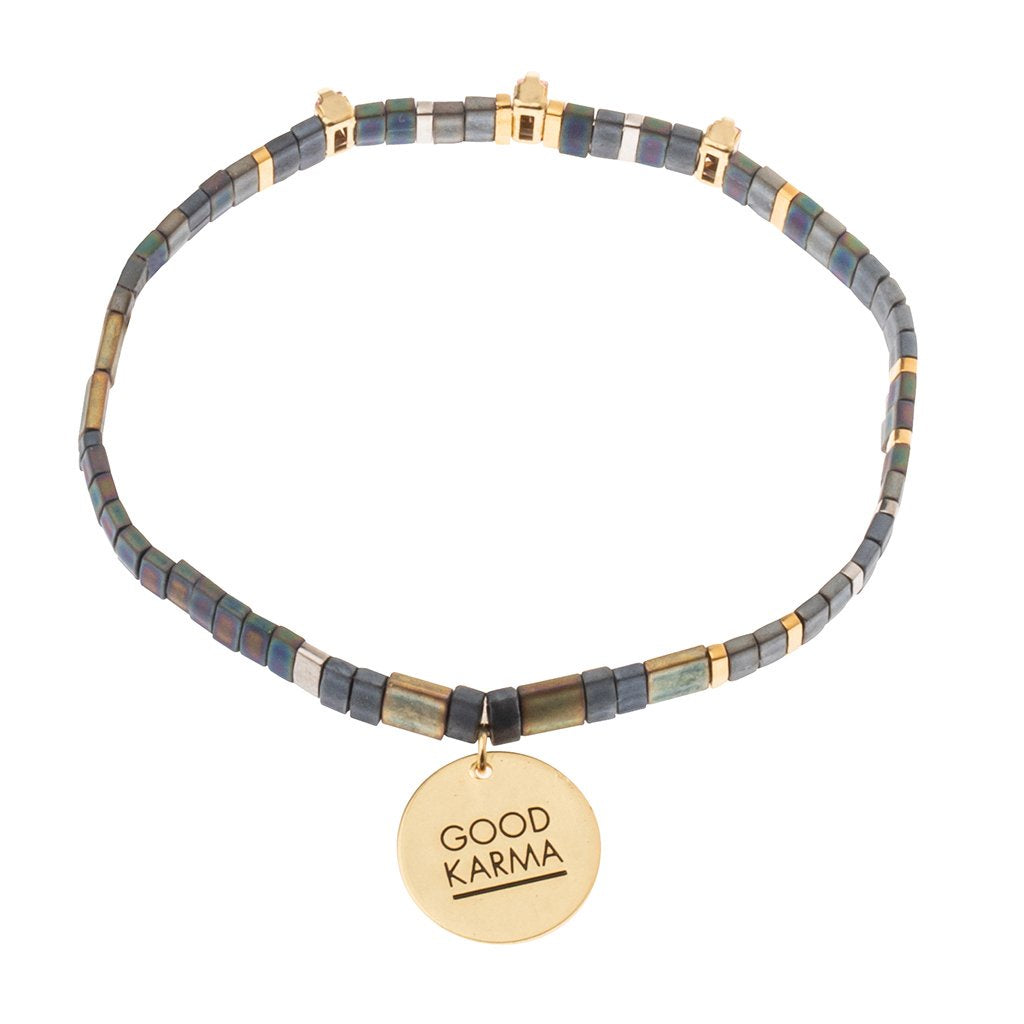 Bracelet in shades of grey blue, gold, and silver beads with a gold charm that says "GOOD KARMA"