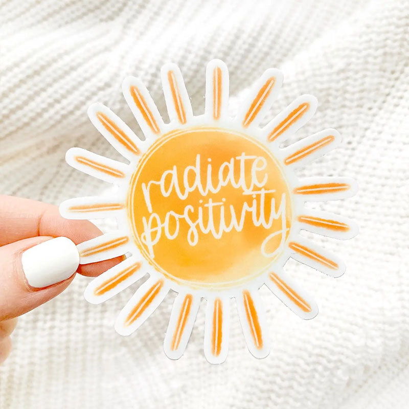Sticker shaped like the sun with rays shining out and "radiate positivity" written in the middle of the sun