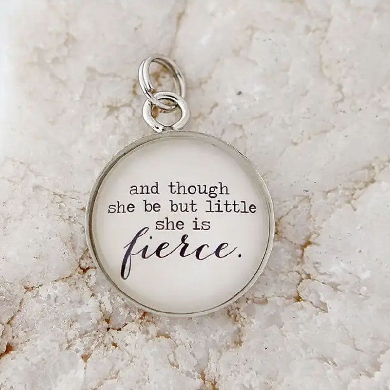 Round white necklace pendant with silver metal edge that reads "and though she be but little she is fierce."