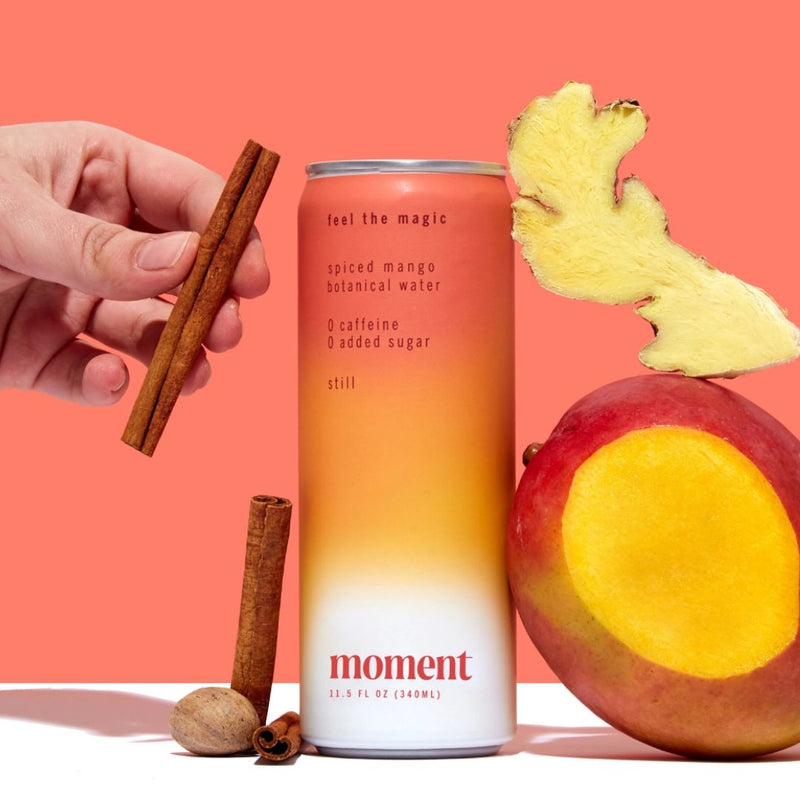 Can of Spiced Mango botanical water with sticks of cinnamon and a mango fruit