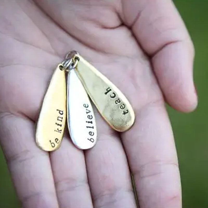 Hand holding 3 teardrop pendants to show scale