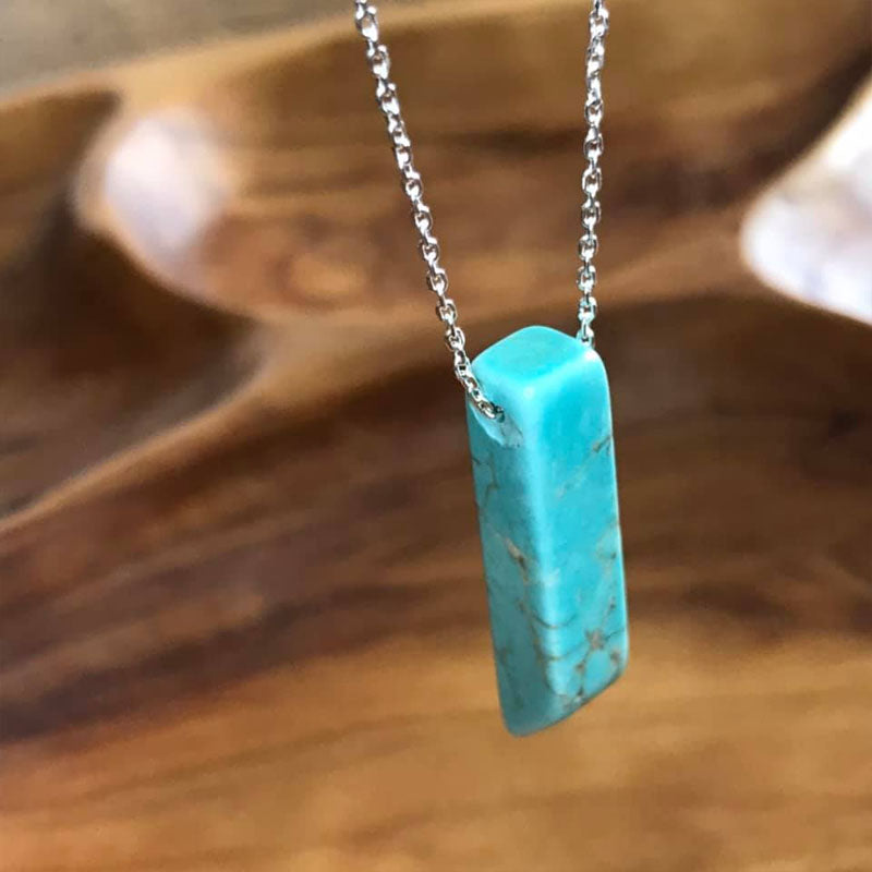 A beautiful turquoise stone pendant shaped into a point at one end hanging from a sterling silver dipped chain.