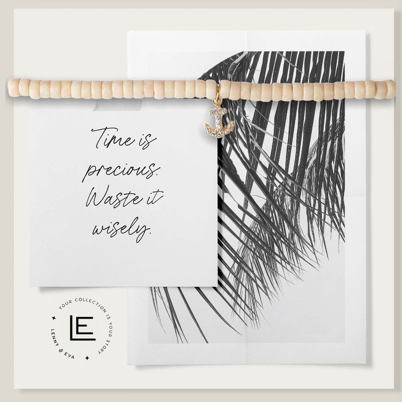 Ivory colored beaded bracelet with a tiny cubic zirconia anchor charm. On a card that reads "Time is precious. Waste it wisely" Image of palm leaf on card.