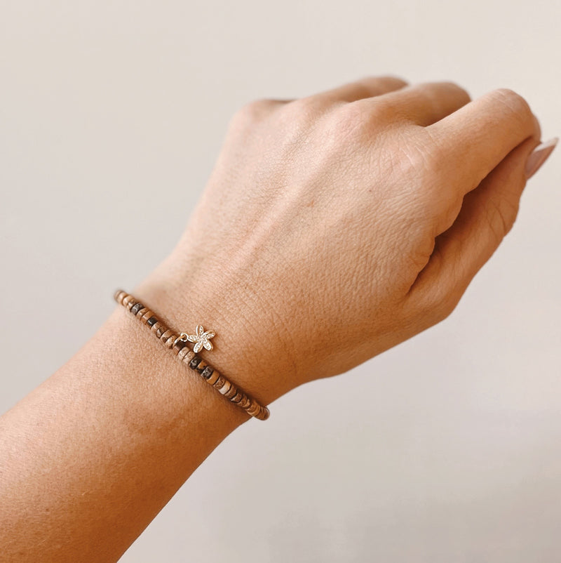 Brown beaded bracelet with starfish charm on model's wrist