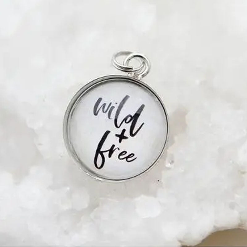 Round white necklace pendant that reads "wild and free".