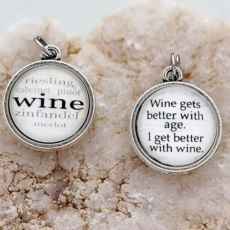 Reversible necklace pendant that has the word "wine" with a list of different wines on one side and on the reverse says "Wine gets better with age. I get better with wine."