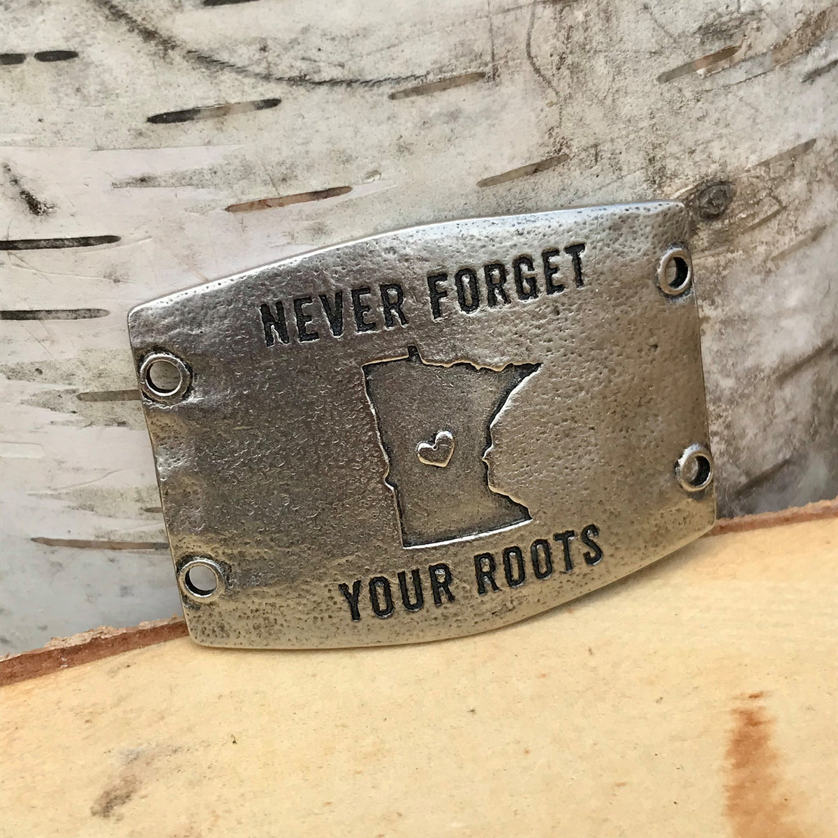 Antique silver finish Lenny & Eva bracelet sentiment that reads, "Never forget your roots" Design in the middle of the sentiment is a heart inside an outline of the state of Minnesota.