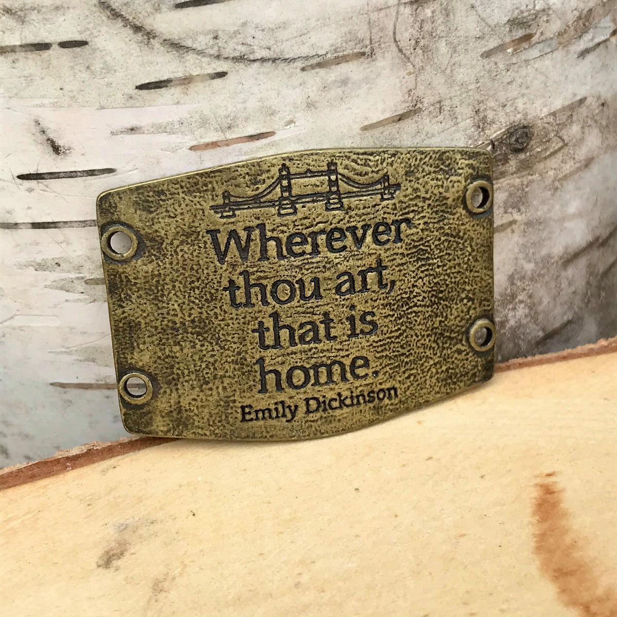 Antique brass colored Lenny & Eva bracelet sentiment that reads, "Wherever thou art, that is home." Quote by Emily Dickinson. Adorned with a bridge design above the quote.
