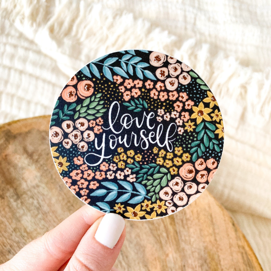 Round black sticker with floral design that says "love yourself"